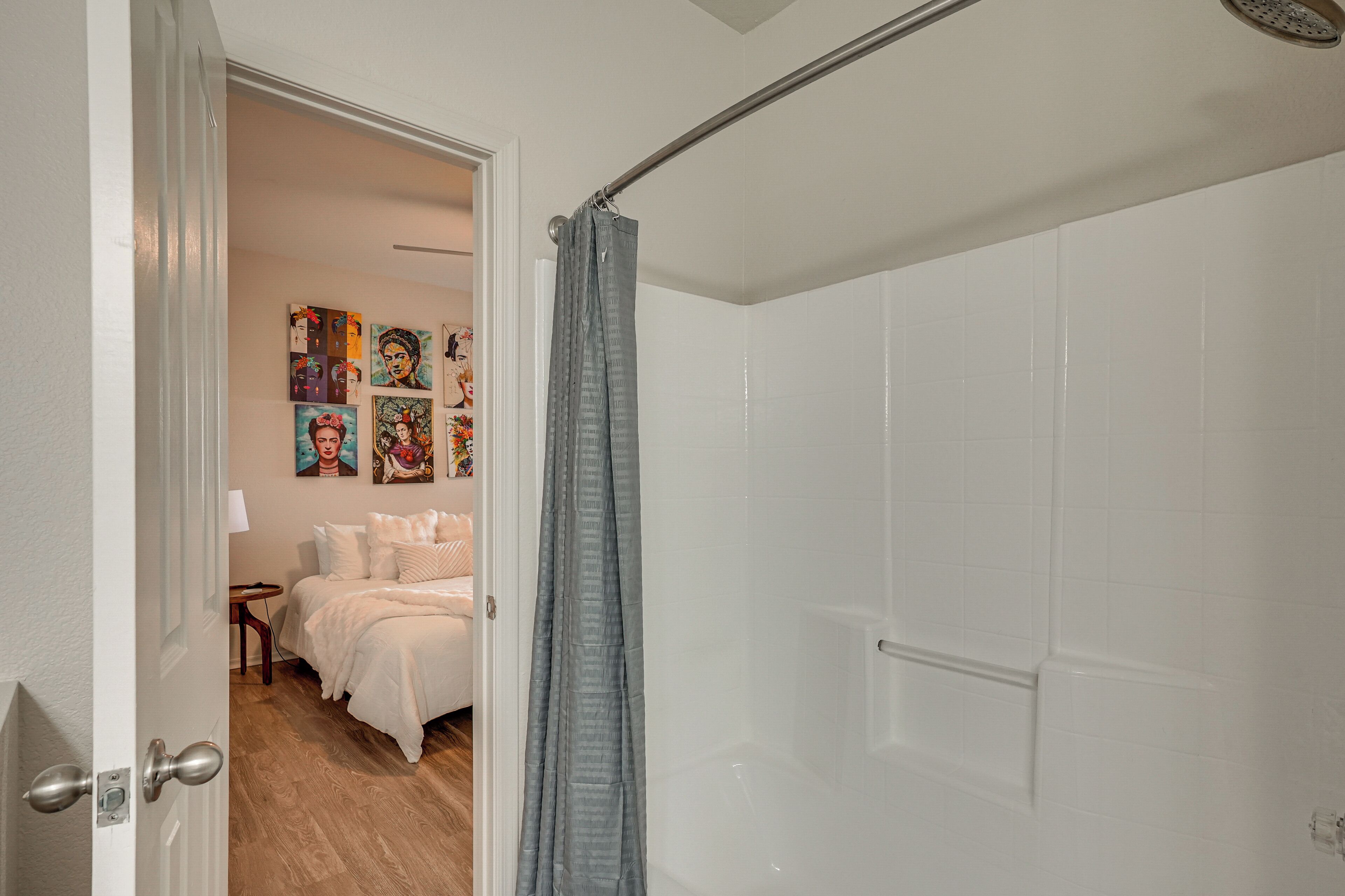 A bedroom with a bed, a nightstand, and a wall with colorful artwork.