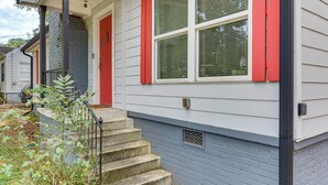 Ein Haus mit einer Veranda, einer roten Tür und einer Treppe, die zum Eingang führt.