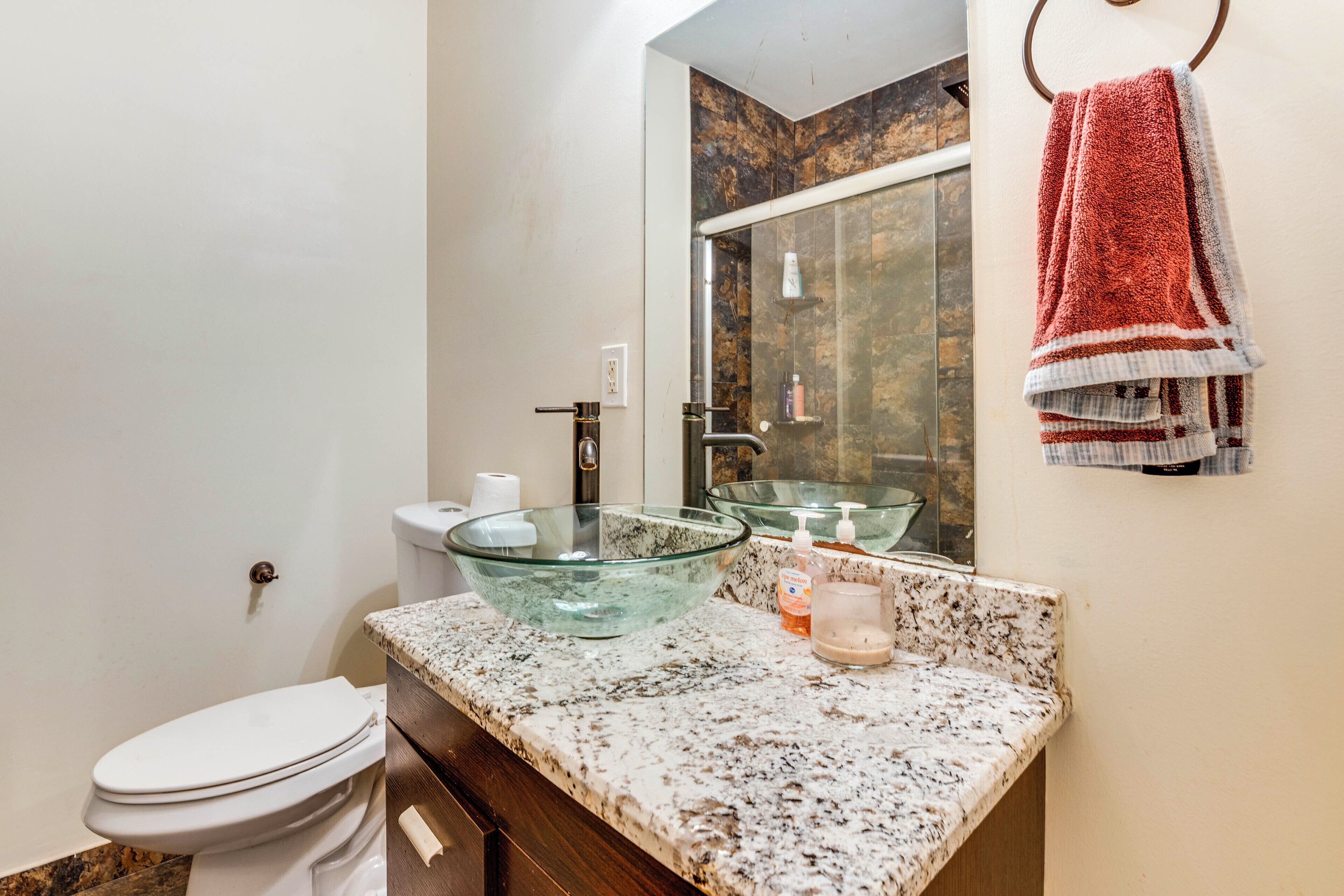 Un bagno con un lavabo in vetro, un water e un asciugamano su un portascopevoli.