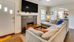 Ein Wohnzimmer mit Kamin, einem darüber montierten Fernseher, einem Deckenventilator und einem Sofa.