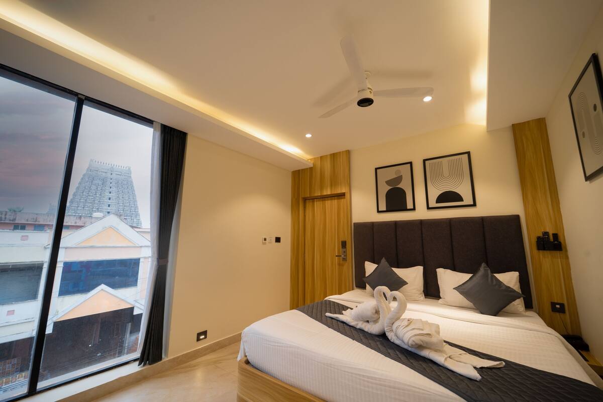 Een moderne hotelkamer met een groot bed, een plafondventilator en uitzicht op de stad.