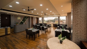 Un restaurante moderno con suelo de madera, mesas redondas y sillas negras.