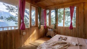 A wooden cabin room with a bed, curtains, and a view of a lake. - DUPLEX TREEHOUSE- TANDI -WIFI (Tandi)