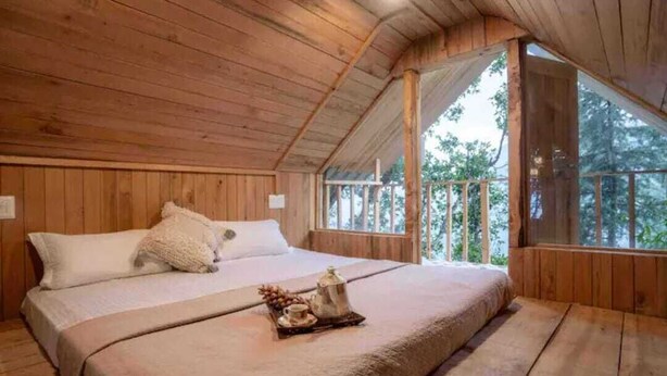 A wooden cabin bedroom with a bed, pillows, and a tray with a teapot and fruit. - DUPLEX TREEHOUSE- TANDI -WIFI (Tandi)