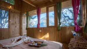 A wooden cabin room with a bed, a window with curtains, and a table with breakfast items. - DUPLEX TREEHOUSE- TANDI -WIFI (Tandi)