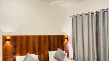A hotel room with a wooden headboard, a bed with white and gray bedding, a nightstand with a phone, and a ceiling fan.