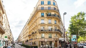 A multi-story building with a cafe on the ground floor, balconies, and a street view. - Cosy Paris apartment 5 minutes from Bastille! Ideal for sightseeing! (Paris)