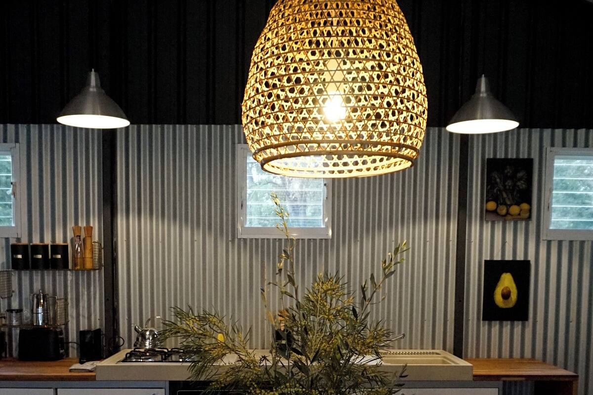 A modern kitchen with a central island, two pendant lights, and a hanging light fixture.