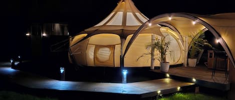 A dome-shaped tent with a wooden deck and potted plants.
