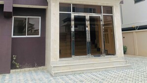 A building with a dark facade, multiple windows, and a central entrance with glass doors. - City Residence Lagos (Lagos)