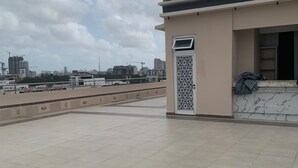 A rooftop terrace with a tiled floor, a small building with a decorative door, and a view of the city skyline in the background. - City Residence Lagos (Lagos)