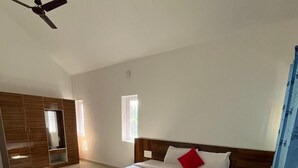 Un dormitorio con una cama grande, un armario, un ventilador de techo y una ventana.