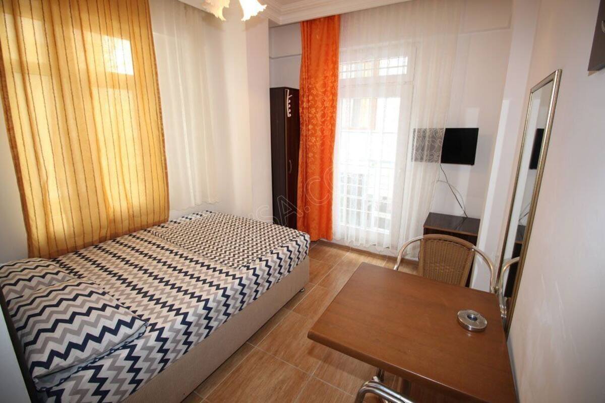 Ein Hotelzimmer mit Bett, Schreibtisch, Stuhl, Fernseher und Kleiderschrank.
