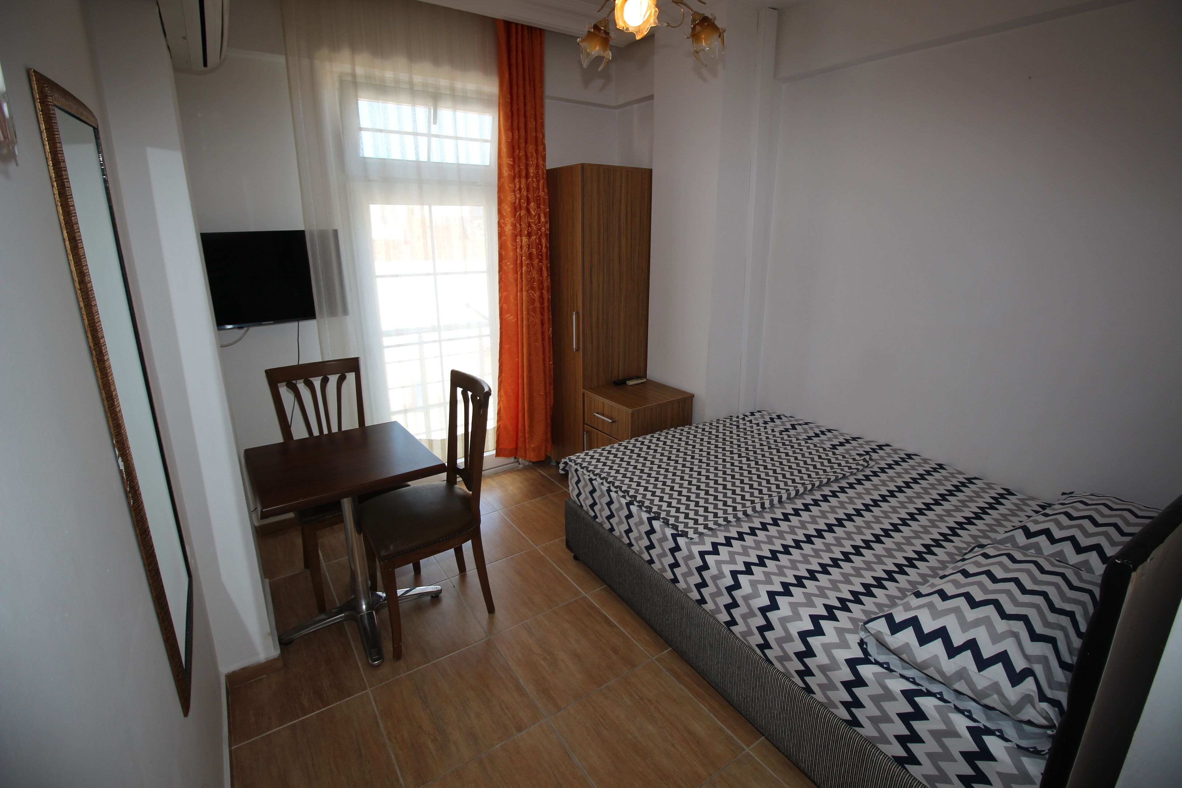 Un dormitorio con cama, escritorio, silla, armario y televisor.