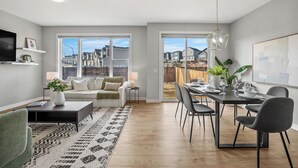 A modern living room with a sofa, coffee table, and dining area with chairs and a table.