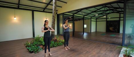 A spacious indoor area with a high ceiling, wooden flooring, and potted plants.