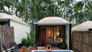 A swimming pool with a covered area, surrounded by lush greenery and tall palm trees. - Hipnoetic Goa -Private Pool Cottages (Quepem)