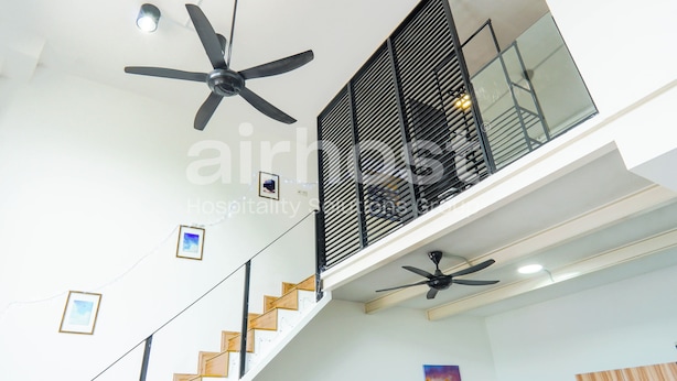 A modern hotel interior with a staircase, multiple ceiling fans, and a glass railing on the upper level. - Empire City Damansara M Tower by Airhost (Petaling Jaya)