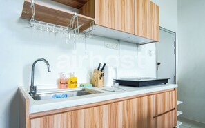 A modern kitchen with wooden cabinets, a stainless steel sink, and a built-in dishwasher. - Empire City Damansara M Tower by Airhost (Petaling Jaya)