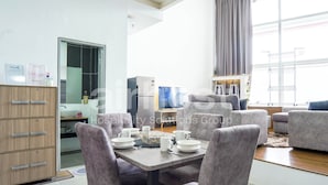 A modern hotel room with a dining area, a kitchenette, and a large window with curtains. - Empire City Damansara M Tower by Airhost (Petaling Jaya)