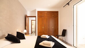 Een hotelkamer met een bed, zwart-wit beddengoed, een houten garderobe, een stoel en een raam.