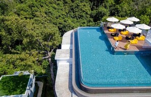 An aerial view of a swimming pool with a deck area, surrounded by lush greenery. - 1BR Loft Pool Gym  Walk to Naiharn C181 (Rawai)
