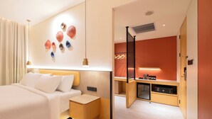 Una habitación de hotel moderna con una cama grande, un escritorio pequeño y una kitchenette.