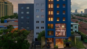 Un moderno edificio de hotel con varios pisos, amplias ventanas y una entrada visible.