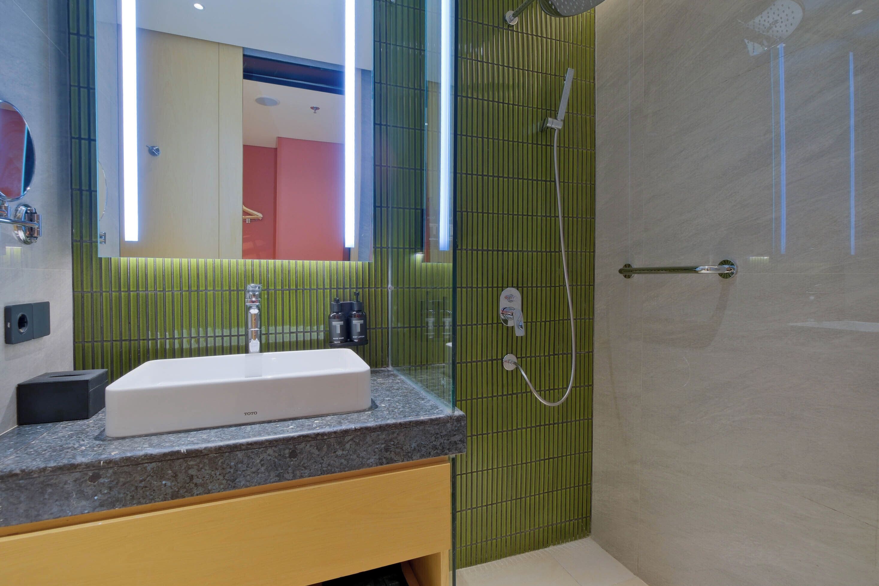 A modern bathroom with a rectangular sink, a glass shower enclosure, and a mirror with a light strip.