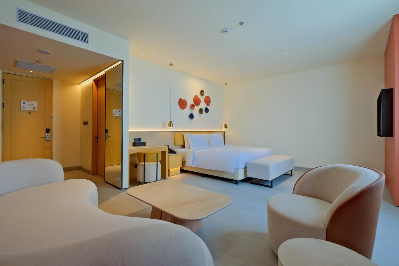 A modern hotel room with a bed, a desk, a chair, and a TV.