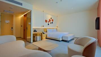 A modern hotel room with a bed, a desk, a chair, and a TV.