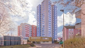 Een meerlaags woongebouw met een modern ontwerp, met een centrale binnenplaats en een combinatie van balkons en ramen.