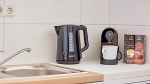 Een keuken met een zwarte Philips koffiezetapparaat, een witte mok en twee pakken koffiemelk.