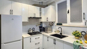 A modern kitchen with white cabinets, a built-in stove, a microwave, and a sink. - Zarafshan city 64 Tashkent (Tashkent)