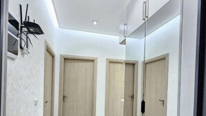 A modern hallway with a mirrored wall, light wood doors, and a marble-patterned floor. - Zarafshan city 64 Tashkent (Tashkent)