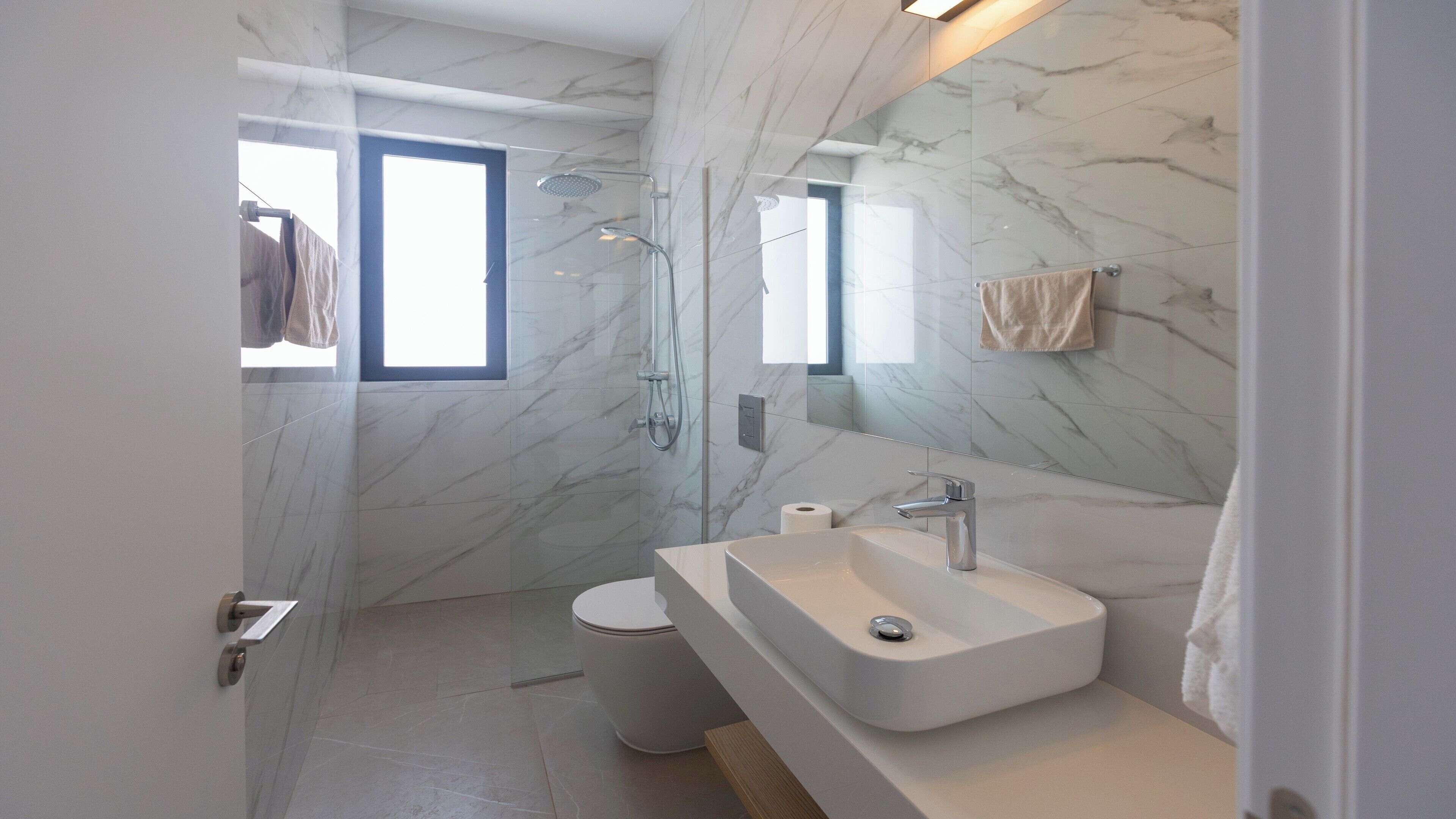 A modern bathroom with a large mirror, a sink, and a shower.