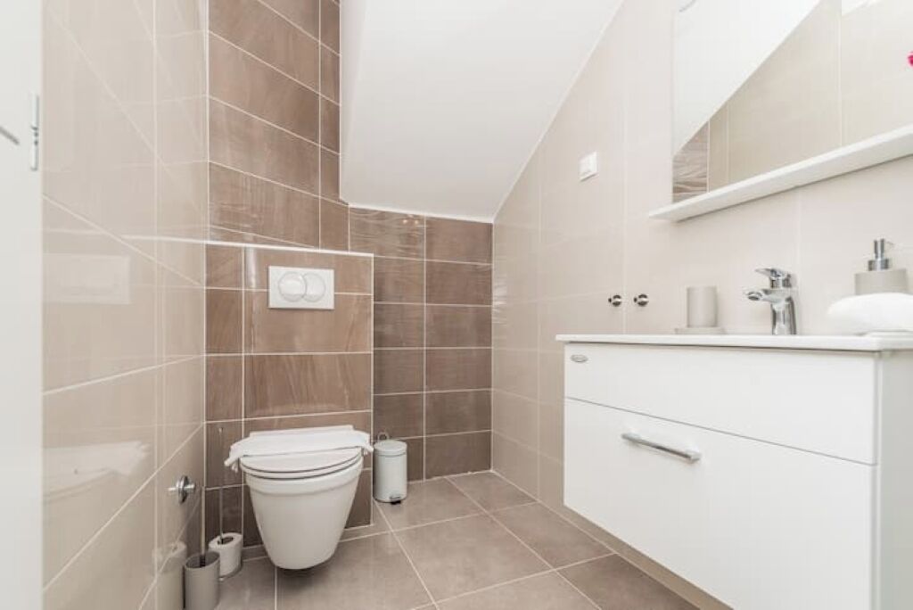 Ein modernes Badezimmer mit Toilette, Bidet und Stauraumschrank.