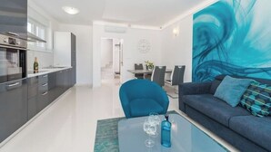 Una sala de estar moderna con un sofá, una mesa de centro de vidrio y un comedor con una mesa y sillas.