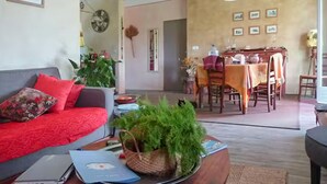 Een woonkamer met een bank, een eettafel met stoelen, en een keuken in de achtergrond.