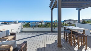 Terraço no telhado com pérgola, móveis de vime e vista para o oceano.
