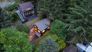 Ein zweistöckiges Haus mit Terrasse und Garage, umgeben von dichtem Wald.