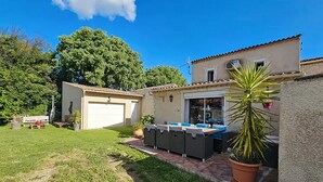 Una propiedad residencial con garaje, un patio con mobiliario exterior y un césped bien cuidado.