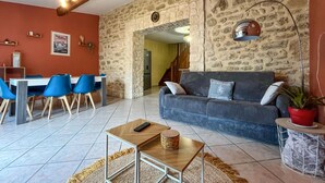 Una sala de estar acogedora con una pared de piedra, un sofá azul y un comedor con sillas azules.