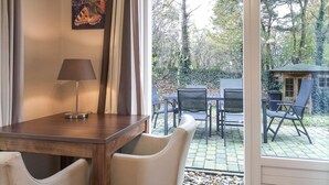 A room with a wooden table, a lamp, and a view of an outdoor patio with chairs and a small structure. - Cozy home in Lemele with heated swimming pool (Lemele)