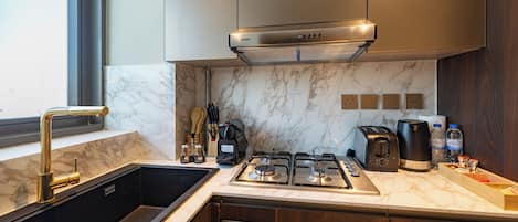 Et moderne køkken med emhætte i rustfrit stål, indbygget ovn og vask.