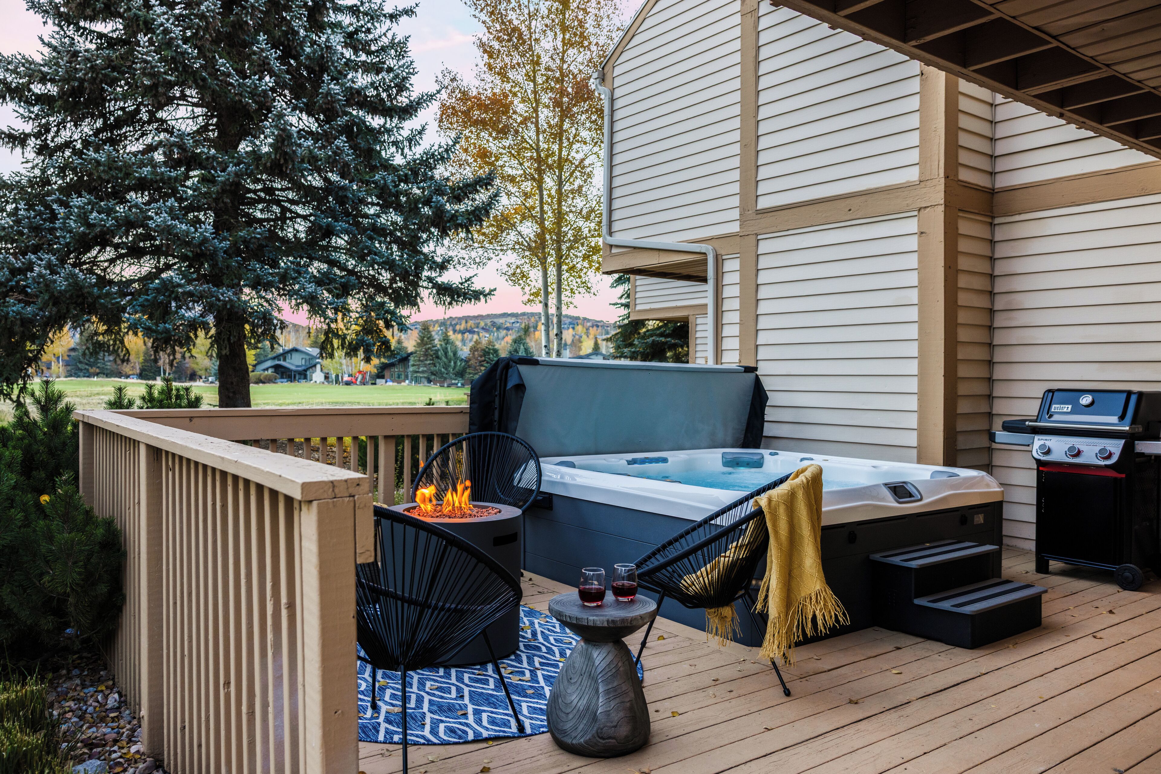 Una terraza con jacuzzi, parrilla y mobiliario exterior.