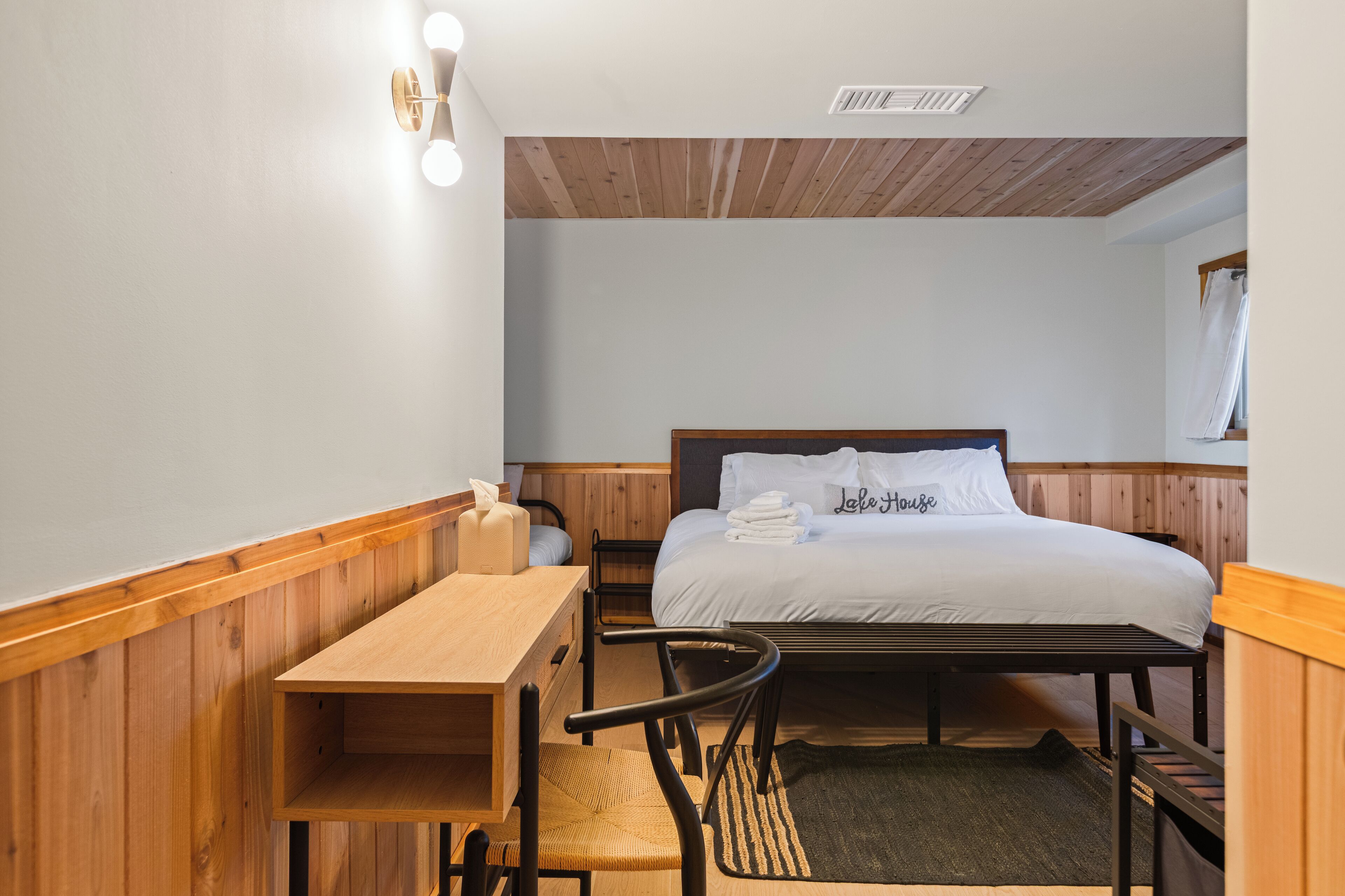 Un dormitorio pequeño y ordenado con una cama de madera, un escritorio y una silla.
