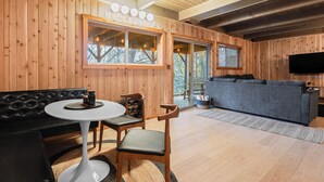 Un ambiente accogliente in legno, con un divano in pelle nera, un tavolo rotondo bianco e un divano grigio.