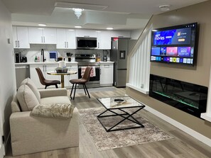 Una cocina moderna con armarios blancos, microondas integrado y refrigerador de acero inoxidable.