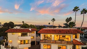 Ein modernes, zweistöckiges Haus mit rotem Ziegeldach, großen Fenstern und einem Balkon.